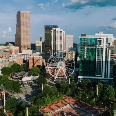A panoramic view showcasing the vibrant Atlanta skyline with a Ferris wheel in the foreground.